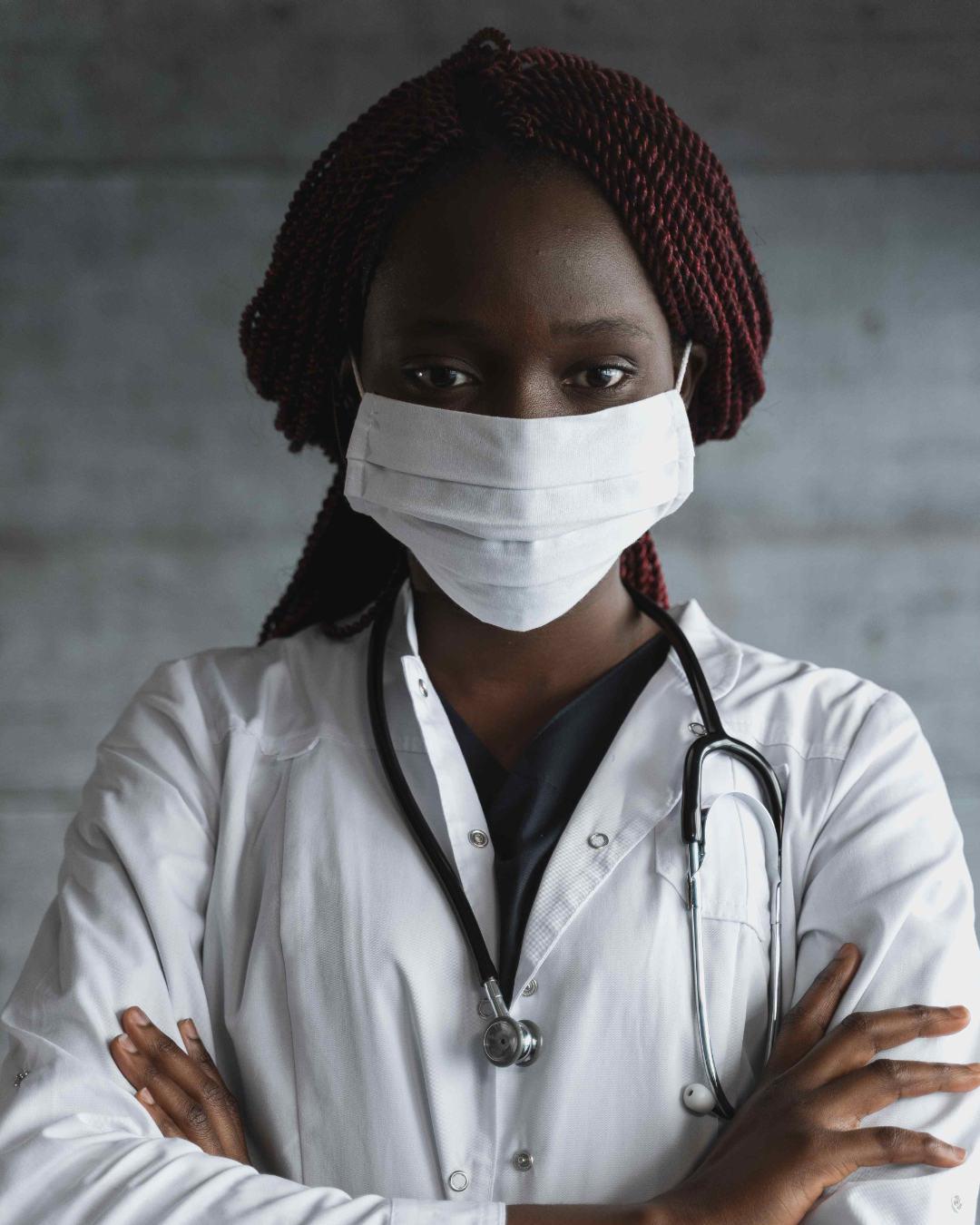 Image of doctor, arms crossed across chest, wearing a a mask over their face and a stethoscope around their neck. 